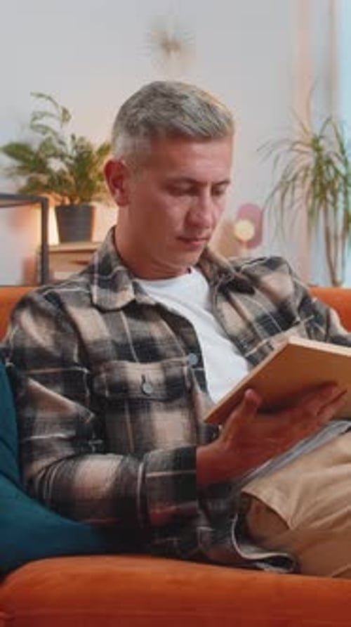 Man Sitting on a Couch Reading a Book
