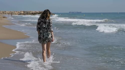 Young Girl Walks Along the Beach of the Sea Coast in Slow Motion
