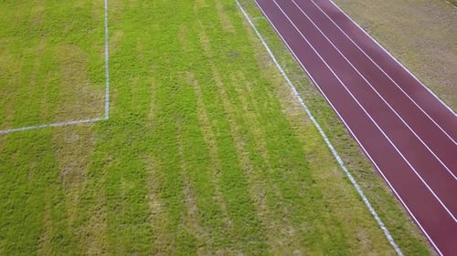 Top View of Red Running Tracks and Green Grass Lawn