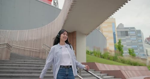 Attractive Young Asian Woman with Headphones Walking at the City