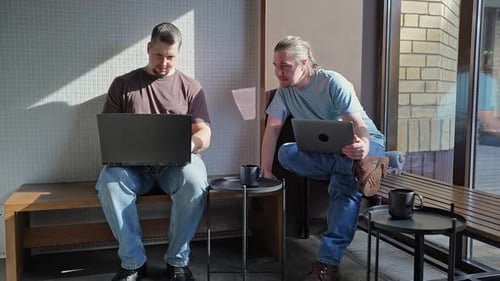 Deux ingénieurs logiciels de Laughing It travaillent sur un projet et une programmation dans un café avec succès