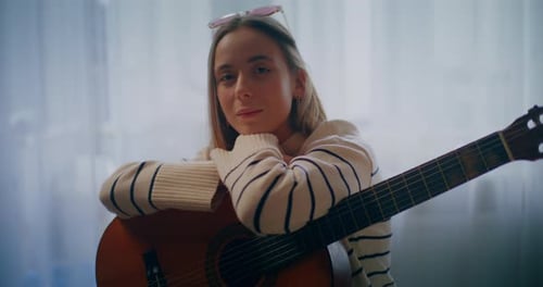 Young Woman with Guitar Leaning Against Instrument