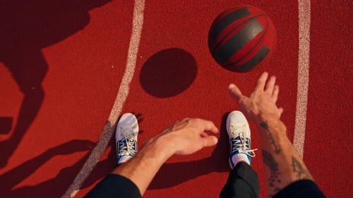 Close-up of a basketball guy's shadow on the floor of a basketball court while dribbling the ball