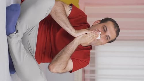 Vidéo verticale d'un homme qui se couvre la bouche et le nez pendant qu'il éternue.