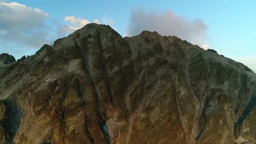 Picturesque view over rocky mountains peak at dusk. Flying over rugged alpine mountainous summits. D
