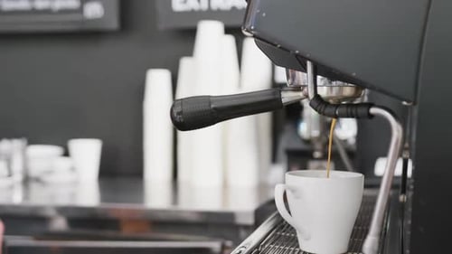 Caucasian male barista preparing coffee with coffee machine in cafe