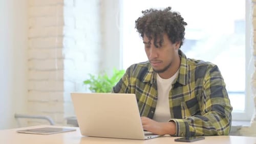 Young Adult Works on Laptop in Bright Home Setting