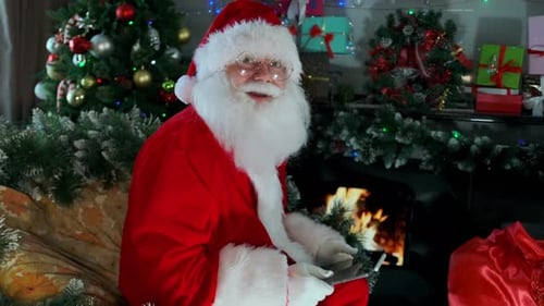 Santa Claus Using Tablet by Christmas Tree