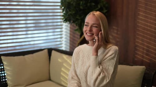Blonde Woman Talking Animatedly on Phone Indoors