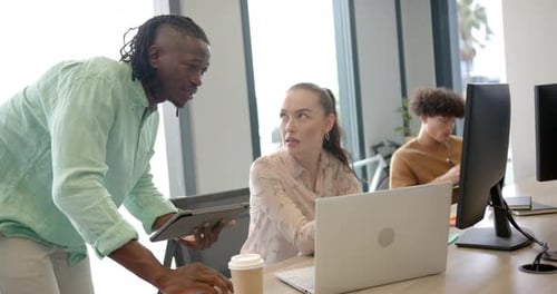 Collaborating in office, colleagues discussing project using laptop and tablet