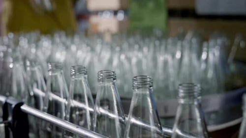 Des bouteilles de verre vides sur un convoyeur indiquent la production de boissons alcoolisées d'une distillerie moderne et