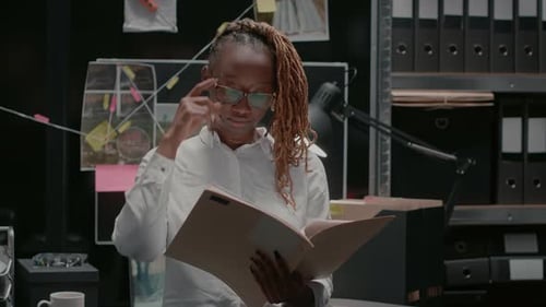 Thoughtful Woman Looks Through Documents in Office
