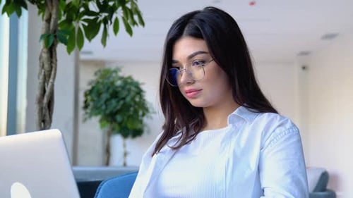 Happy Young Girl Working at a Coffee Shop with a Laptop