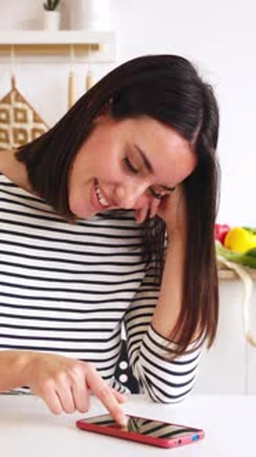 Smiling Woman Using Smartphone in Modern Kitchen