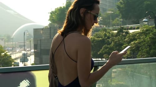 Young Woman Texting on Smartphone Walking in City,