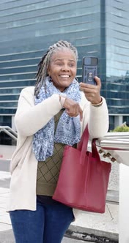 Vertical video: African American senior woman retrieving smartphone at plaza tapping preparing call