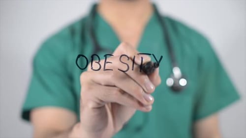 Doctor Writing the Word Obesity with a Marker