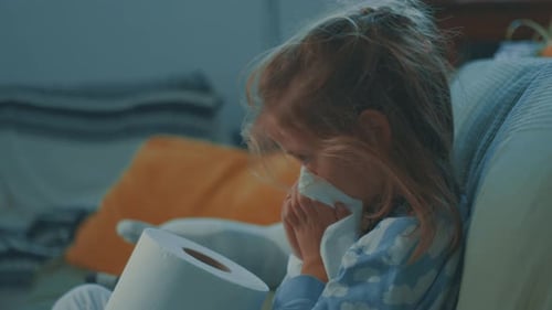 Sick Child Wiping Nose with Toilet Paper on Couch