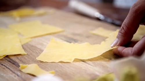Cutting Pasta Dough into Squares on Wooden Board