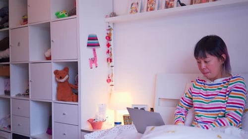 Young Woman Types on Laptop in Bed