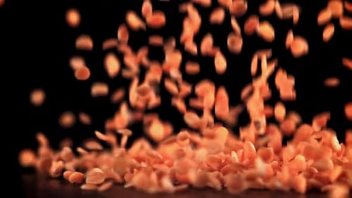 Red Lentils Falling in Slow Motion on Black Background