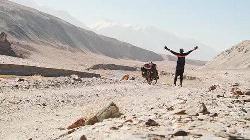 Cyclist Celebrates Journey Through Desert Landscape