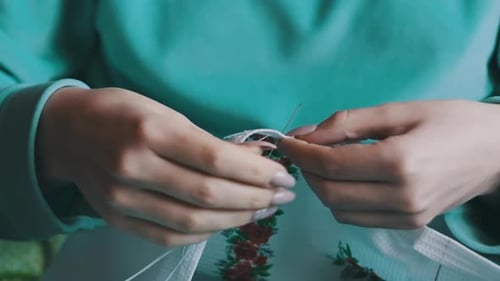 Woman Sewing Beautiful Floral Pattern on Fabric