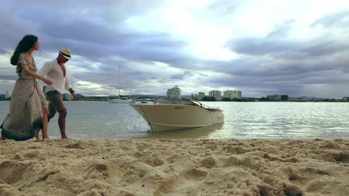 Beautiful Young Caucasian Couple Walking on the Beach, Holding Hands Under A