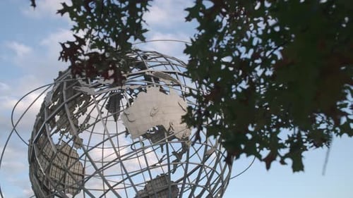 World Globe Sculpture Framed by Tree Branches Outdoors