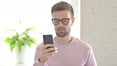 Young Man Browsing Internet on Smartphone