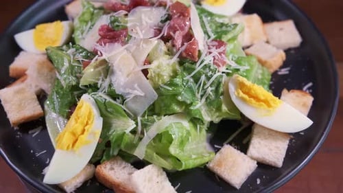 Ein köstlicher frischer, gesunder Caesar-Salat, der sich auf einem schwarzen Teller mit Nahaufnahme dreht