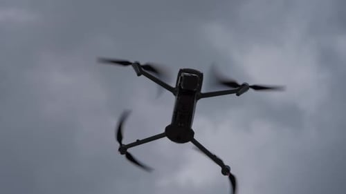 Quadcopter Drone Flying Against Cloudy Sky Concept of Drone Flight