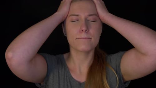 Young woman is despairing. The woman cries about her problems, raises her hands to her forehead.