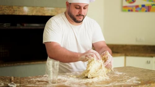 Chef Kneading Dough in Kitchen