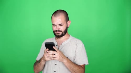 man replying to messages with joy in front of green screen