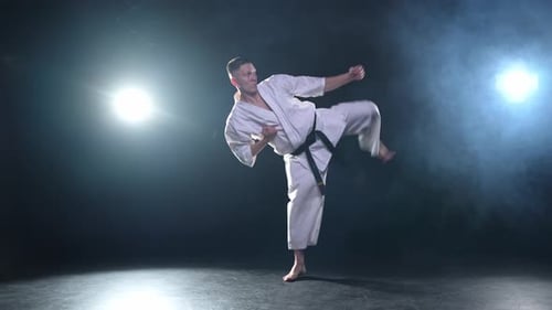Starker Kämpfer im weißen Kimono für Karate-Kampfkünste mit schwarzem Gürtel bereitet sich auf den Kampf vor