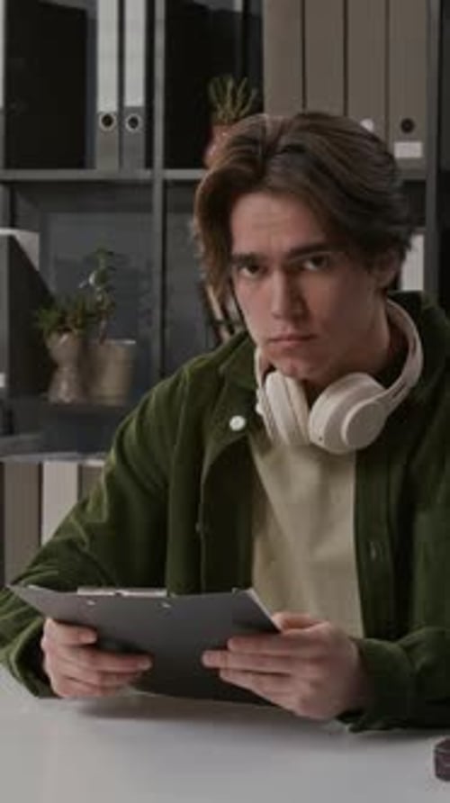 Young Man Reviewing Documents Wearing Headphones
