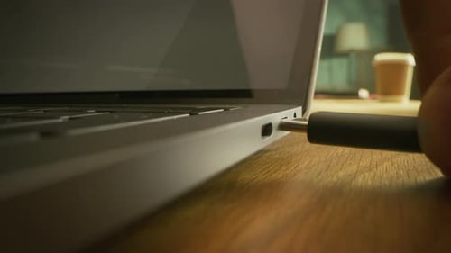 Close-up Macro Shot: Laptop on the Desk, Person Inserts USB-C Cable Adapter into Computer Port.