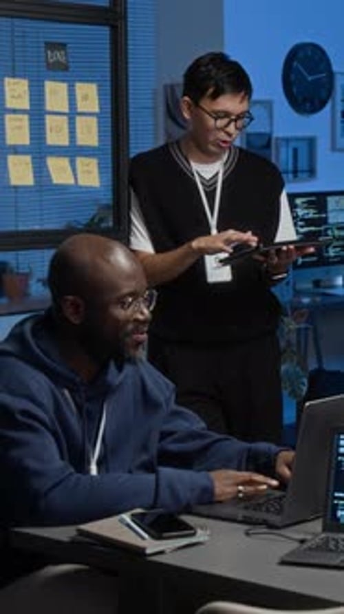 Two Men Work Together on Computer Code in Office
