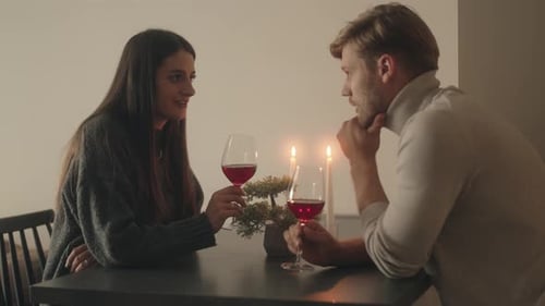Romantisches Paar genießt Wein und Abendessen bei Kerzenschein zu Hause
