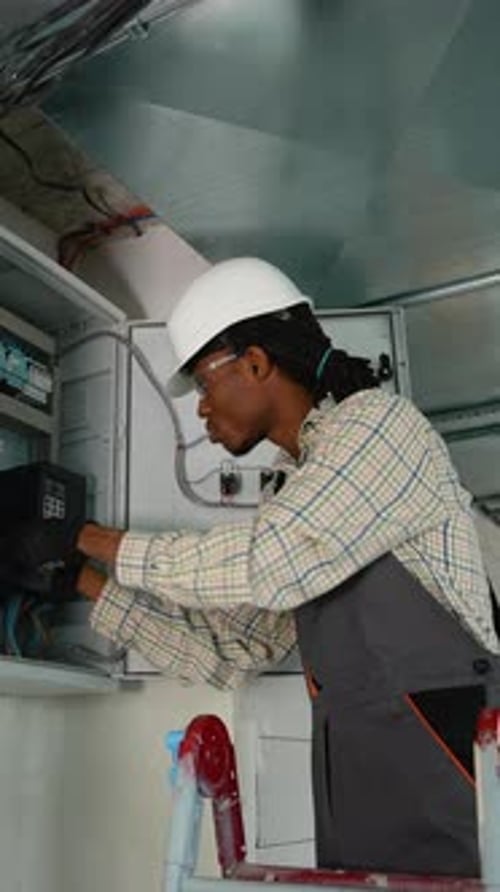 Electrician Working on Electrical Panel Installing a New Device