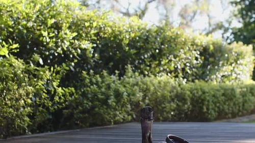 Water bottle, headphones, towel and yoga mat on deck in sunny garden, copy space, slow motion
