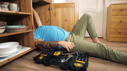 Top View of Repairman Lying Under Sink in Kitchen Fixing or Cleaning Pipes