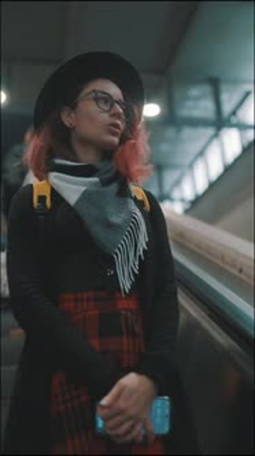 Stylish Young Woman with Pink Hair Riding an Escalator