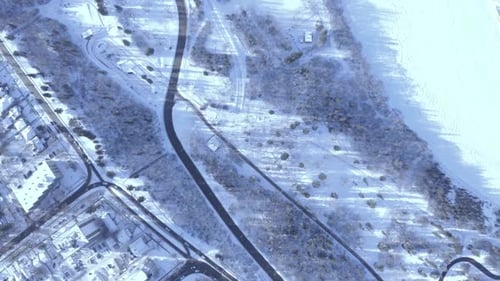 Birds eye view aerial pan left of a highway and an ice snow covered river next to park, next to tow