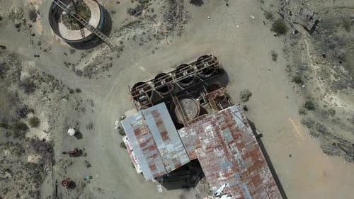 Abandoned warehouse and holding tanks in the desert- aerial ascending