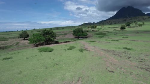Luftaufnahme der tropischen Savannenwiese mit grünen Hügeln und Bergen, Indonesien