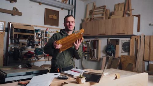 Man Showing Off a Wood Cutting Board in Workshop