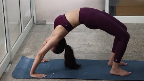 Woman Doing Yoga Wheel Pose Indoors on Mat