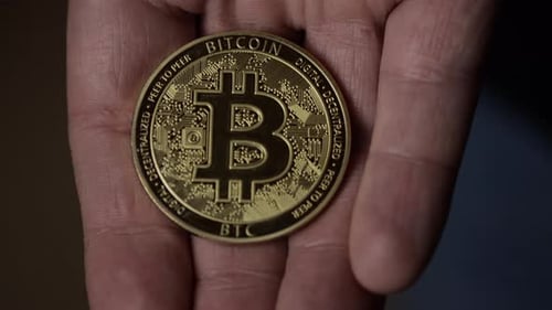 Man shows Bitcoin In His Hand. Bitcoin On Screen. Close Up shot of a golden Bitcoin coin. New financ